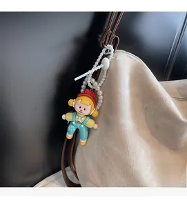 Détail d'un porte-clé fille de dessin animé avec chaîne de perles sur sac cabas