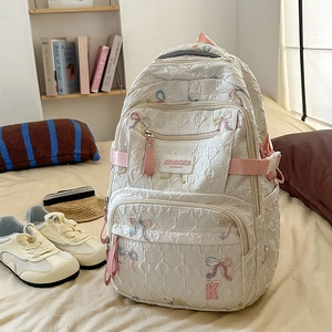 Close-up of cream nylon backpack with bow embroidery and detailed zipper compartments