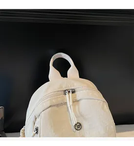 Detail of reinforced nylon top handle and double-headed zipper on cream travel backpack
