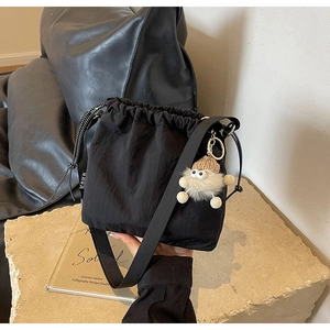 Détail du sac seau en nylon noir avec cordon de serrage et charm monstre en peluche