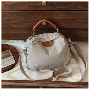 Dettaglio della borsa tote in nylon beige con logo in pelle in un cassetto di legno
