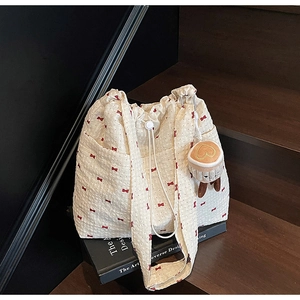 Detail of white tote bag featuring red bow patterns and a coffee cup plush charm