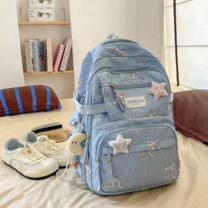 Detail view of light blue quilted backpack with bow embroidery and plush moon charm