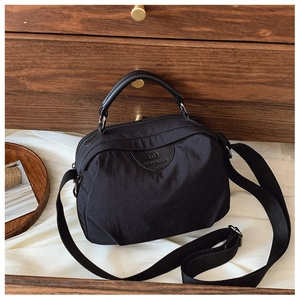 Dettaglio del tessuto in nylon nero impermeabile e del logo in pelle sulla borsa