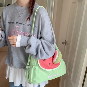 Détail du sac bandoulière pastèque vert clair avec pompons et logo brodé sur le rabat
