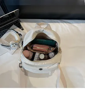 Interior view of white nylon mini backpack showing compartments for phone and essentials