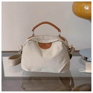 Dettaglio borsa tote in tela con manici in pelle marrone e ganci in metallo argentato