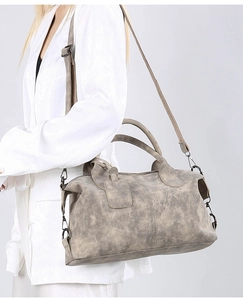 Retro taupe crossbody pillow bag with dual handles and adjustable strap on model