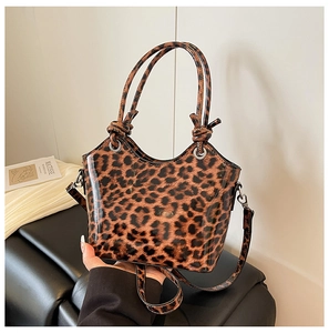 Detail of glossy leopard print handbag featuring knotted handles and silver metal hardware