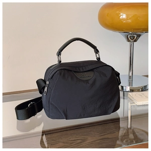 Dettaglio di una borsa a tracolla in nylon nero con manico tondo in PU e tracolla regolabile