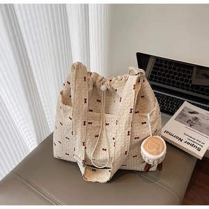 Detail of floral tote bag with red bow pattern, drawstring closure and heart plush charm
