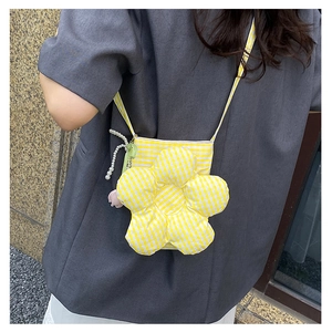 Close-up of yellow checkered flower-shaped crossbody bag with pearl charms and soft fabric