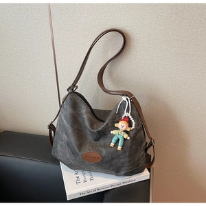 Détail du sac fourre-tout gris foncé avec lanières en cuir marron et breloque mignonne