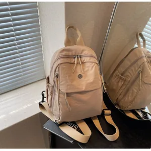 Close-up of beige nylon backpack with textured fabric and front pocket in natural light