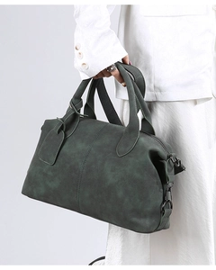 Detail of dark green Boston bag showing matte leather texture and premium gunmetal hardware