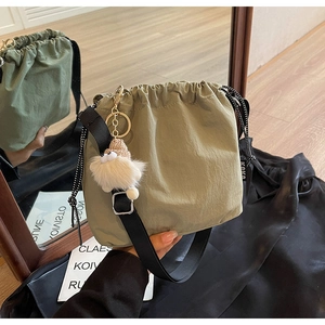 Détail du sac seau vert avec cordon de serrage, étiquette KOKO et charme peluche