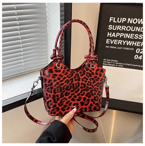 Detail of red and black leopard print handbag with glossy finish and top handles