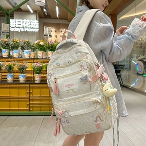 Detail of white quilted backpack with pink K embroidery and cute plush accessories