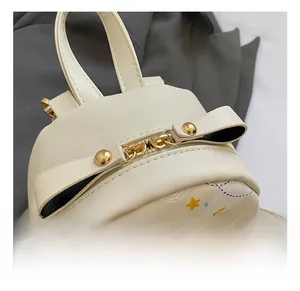Detail of golden zipper hardware with bow decoration on a cream graffiti mini backpack