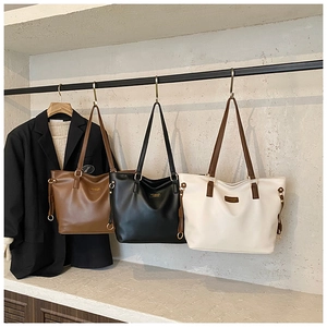 Close-up of minimalist leather tote bags in brown, black and beige on hangers