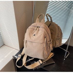 Close-up detail of beige nylon backpack showing fabric texture and side pocket construction