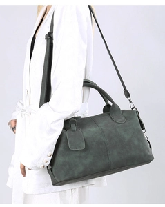 Detail of dark green matte crossbody pillow bag with top handles and adjustable strap