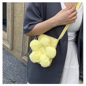 Detail of yellow checkered flower-shaped crossbody bag with pearl accents and slim strap