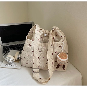 Detail of waffle fabric tote bag with red bow prints and cute coffee plush charm