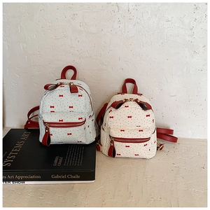 Detail of mini fashion backpacks in light blue and cream with red bow and dot prints