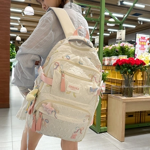 Detail view of cream backpack with quilted pattern and pink bow embroidery for students
