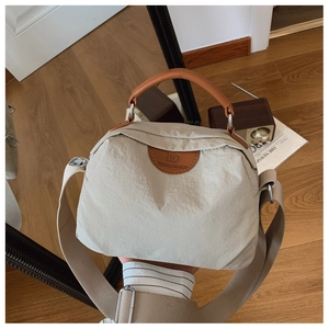 Dettaglio della borsa in nylon beige con logo rotondo in pelle e manico marrone chic