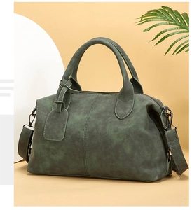 Detail of dark green vintage Boston bag with matte leather texture and dual handles