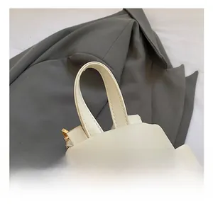 Close-up of cream white leather mini backpack showing the top handle and golden zippers
