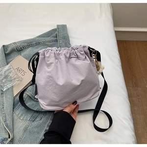 Gros plan du sac seau lavande avec cordon de serrage, bandoulière noire et pompon