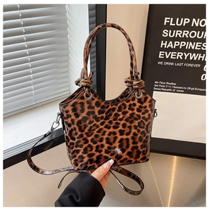 Detail of leopard print tote bag with knotted handle and glossy leather texture