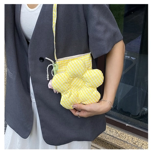 Detail of yellow checkered flower shaped crossbody bag with pearl strap and pink pendant
