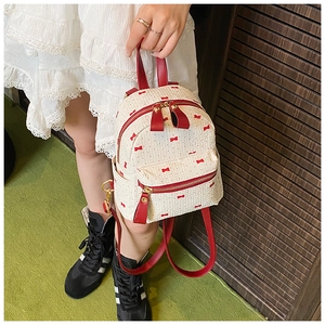 Detail of a mini backpack featuring red bow prints and high-quality leather handles