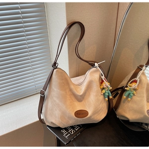 Détail du sac cabas beige avec bandoulière en cuir marron et breloque en perles colorées