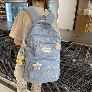 Detail of light blue quilted backpack featuring colorful bow embroidery and star charm