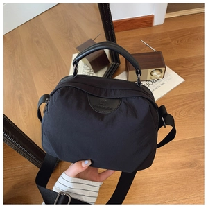 Dettaglio borsa a tracolla in nylon nero con logo in pelle e ampia tracolla
