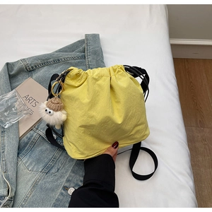 Gros plan sur un sac seau jaune en nylon avec un adorable pendentif monstre peluche
