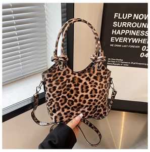 Detailed view of leopard print handbag with glossy finish and knotted top handle strap