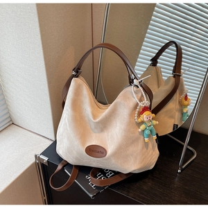 Détail du sac cabas en toile avec poignées en cuir marron et pendentif personnage mignon
