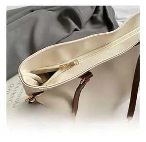 Detail view of high-quality gold zipper and hardware on cream white tote bag