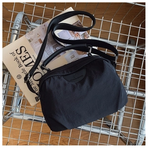 Dettaglio della borsa a tracolla in nylon nero in un cesto con riviste di moda