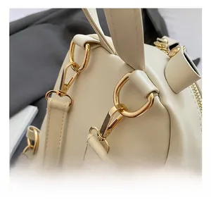 Detailed close-up of premium gold-toned metal hooks and hardware on a cream leather bag