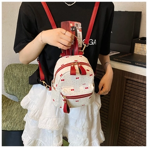 Detail of mini white woven backpack with red bow print and red leather straps