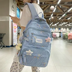 Detail of light blue quilted backpack with bow embroidery and plush star moon charms