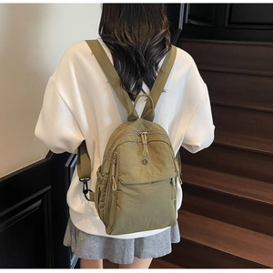 Olive green nylon mini backpack detail showing adjustable straps and multi-pocket design