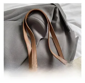 Close-up of white leather tote bag with brown leather handles and gold square hardware